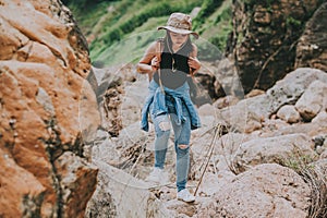 Woman with backpack walking on the rock by river in mountain