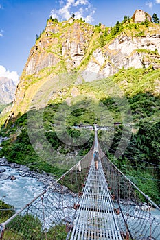 Woman backpacker crossing suspension bridge in Himalayas Nepal