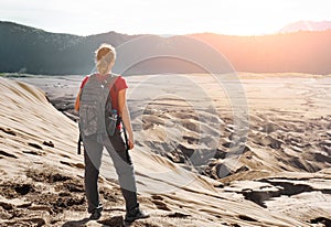 Woman with backpacker enjoying sunrise at desert canyon.