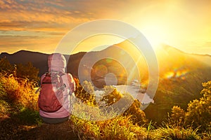 Woman with backpacker enjoying sunrise view at high mountains.