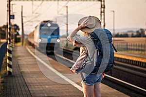 Woman backpacker with hat standing at railroad station