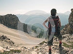 Woman Backpacker hiking in idyllic landscape, waterfall and blooming meadow. Summer adventures and exploration on the Alps. Toned.