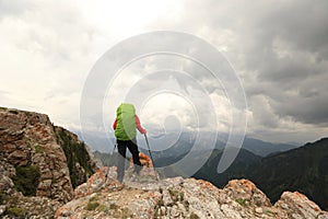 woman backpacker hiking on mountain peak cliff