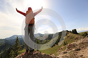 Woman backpacker hiking on mountain peak cliff