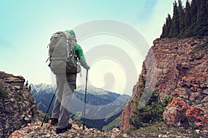Woman backpacker hiking on mountain peak cliff