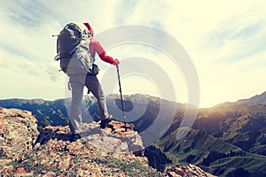 Woman backpacker hiking on mountain peak cliff