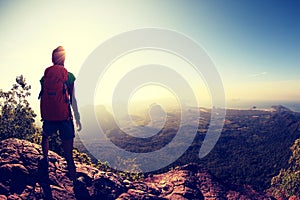 Woman backpacker hiking on mountain peak cliff