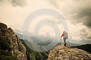 Woman backpacker hiking on mountain peak cliff