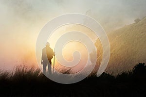 Woman backpacker hiking on mountain peak cliff in the mist