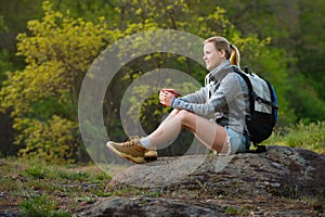 Woman backpacker hiking in summer forest and stopped to have res