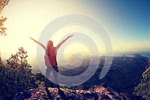 Woman backpacker hiking on sunrise mountain peak cliff