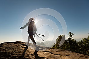 Woman backpacker hiking on sunrise mountain top