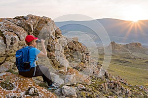 Woman backpacker looks at the landscape through binoculars