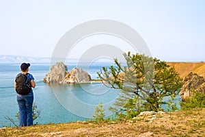 A woman backpacker looks at the Shamanka Rock, Cape Burhan on Olkhon Island. Lake Baikal, Russia