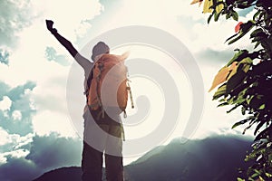 woman backpacker open arms on mountain peak