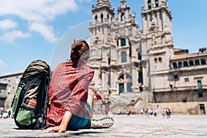 Woman backpacker piligrim siting on the Obradeiro square plaza in Santiago de Compostela