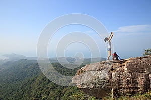 Woman backpacker taking photo with cellphone on mountain peak