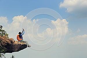 Woman backpacker taking photo on mountain peak cliff