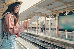 Woman backpacker traveler looking at map with backpack at train station while waiting for train. journey trip travel concept