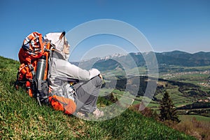 Woman backpacker traveler sitis on the mountain hill with beautiful view on valley