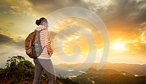 Woman backpacker traveling with backpack standing on top of the photo