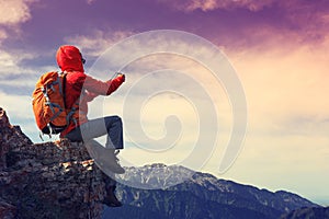 Woman backpacker use digital tablet taking photo on mountain peak cliff