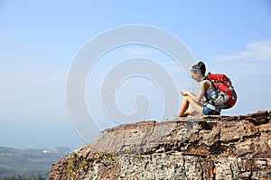Woman backpacker use smartphone on mountain peak
