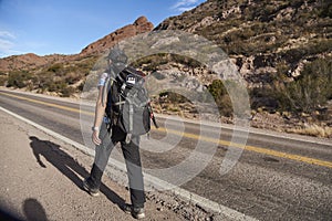 Woman backpacker walking along the roadside, in Mendoza, Argentina