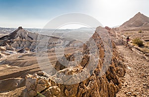 Woman backpacker walking ascending mountain ridge desert trail.