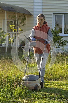 Woman in backyard mowing grass lawn mower