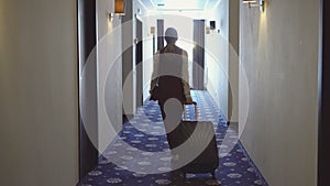 Woman with bags walks the corridor to her room