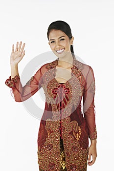 Woman in baju kebaya smiling and waving at the camera. Conceptual image