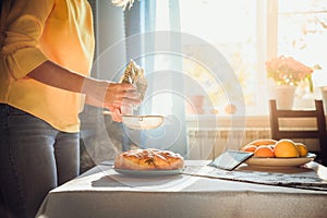 Woman bake fragnant pie and sprinkle the homemade pie with powdered sugar