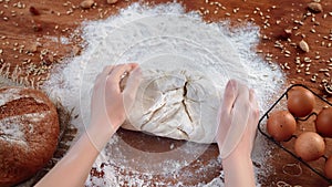 Woman baker kneading dough for bread in home kitchen, homemade bakery, close-up view of female hands