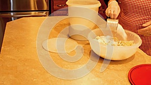 Woman baker measures and transfers three cups of white flour to dough in a large mixing bowl.