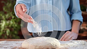 Woman baker pouring raw dough for pie or bread, closeup view of hands and kitchen table at home