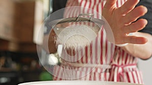 Woman baker sifting flour for dough through bolter.