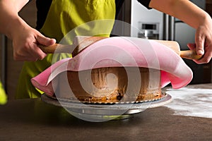 Woman in bakery decorating heart shaped cake with pink royal icing