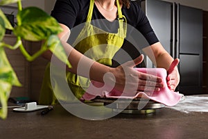 Woman in bakery decorating heart shaped cake with royal icing