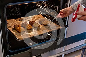 Woman baking fried fish in hot oven in the kitchen as delicious meal for the family as healthy nutrition and a yummy lunch