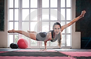 Woman balancing while doing a one hand push up showing strength