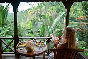 Woman on the balcony of jungle villa with breakfast