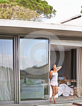 Woman, balcony and waking up with coffee on pajamas in morning, fresh and healthy on bedroom in Los Angeles. Glass door