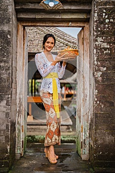 woman with balinese kebaya open her house door in the morning