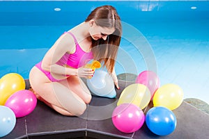 Woman with balloons and cocktail drink at swimming pool.