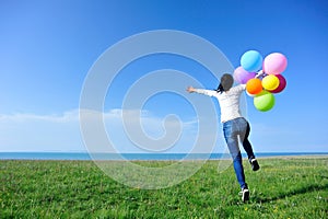woman with balloons jumping on green grassland