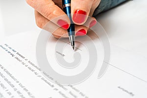 Woman with ballpoint pen signing contract document