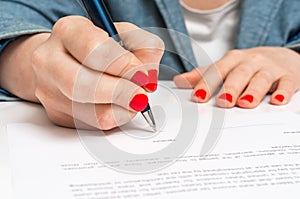 Woman with ballpoint pen signing contract document