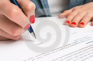 Woman with ballpoint pen signing contract document