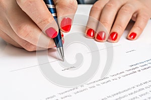 Woman with ballpoint pen signing contract document